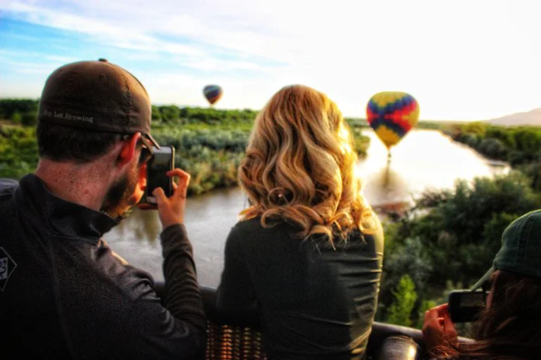 Passengers in a balloon basket photograph two hot air balloons drifting over the Rio Grande